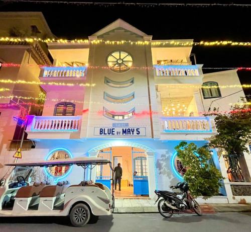 a white golf cart parked in front of a building with lights at Homestay Quan Lan - BLUE by MAY5 in Quan Lạn