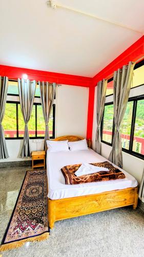 a bedroom with a bed with red walls and windows at Lhamu homestay in Chug