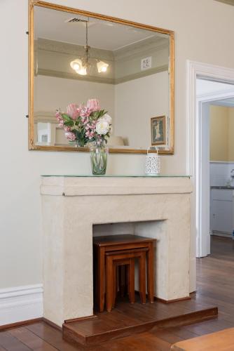 a fireplace with a mirror and a vase of flowers at View House Swan BnB Management in Perth