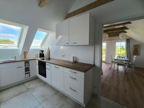 a kitchen with white cabinets and a dining room at Ferienwohnung "Grüne Auszeit" in Groß Wokern