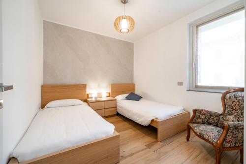 a bedroom with two beds and a chair and a window at Villa Sunshine - Luxury property, with pool & large private garden, few steps from the beach, ideal for families, large groups and people with mobility issuess in Dervio