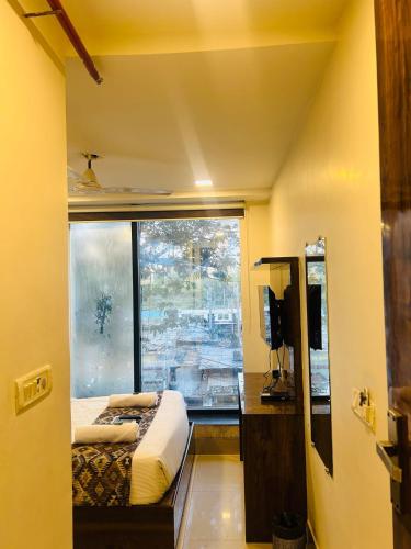 a bedroom with a bed and a large window at Hotel Summer Inn in Mumbai