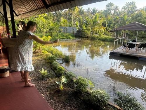 a woman standing on a porch looking at a pond at Steps Garden Resort in Negombo