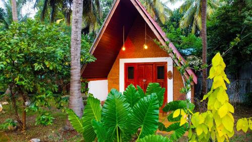 a small house with a red door in a forest at Nature Rest Ashored in Sigiriya