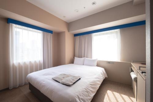 a bedroom with a white bed and two windows at THE BASEMENT HOTEL OsakaHonmachi in Osaka
