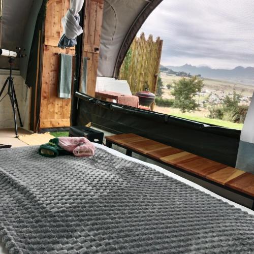 a bed in a room with a view of a field at The Jolly Joint Clarens in Clarens