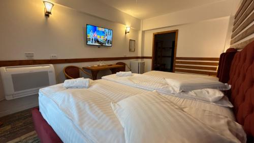 a bedroom with two beds and a tv on the wall at Cabana Sura Getilor Arinis in Voronet