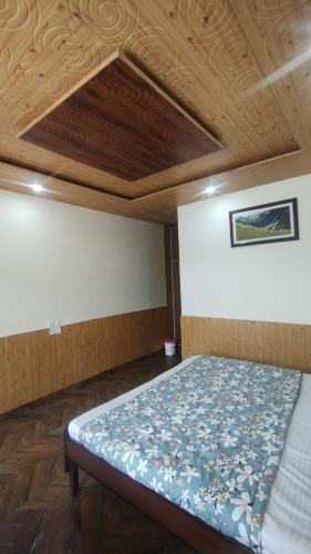 a bed in a room with a wooden ceiling at Himalayan Valvista - Food & Stay in KumhÄrsain