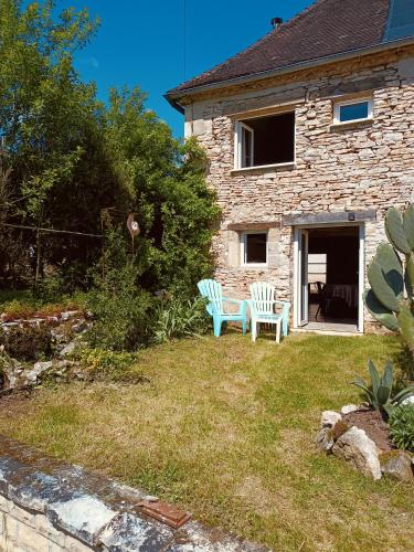 two chairs sitting in the yard of a stone house at Location gîte palette et papillons en Dordogne in Sainte-Eulalie-dʼAns