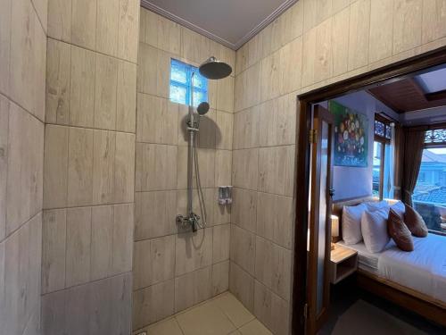 a bathroom with a shower and a bed in a room at Twowi House Ubud in Ubud