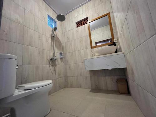 a bathroom with a toilet and a sink and a mirror at Twowi House Ubud in Ubud
