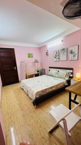 a bedroom with a bed with pink walls and wooden floors at Studio Kéo lưới in Hanoi