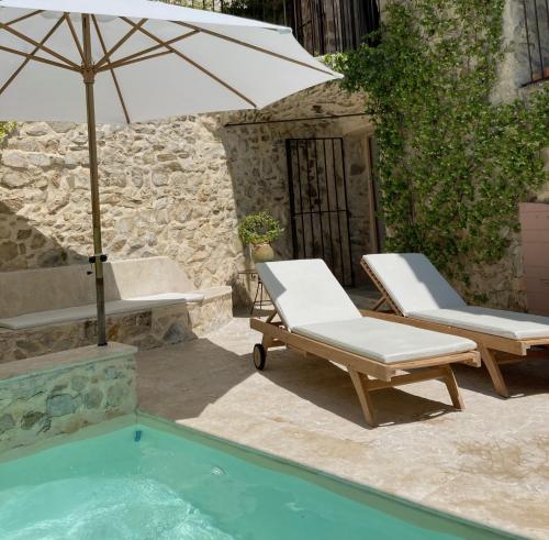 a pair of chairs and an umbrella next to a pool at Les Vieux Murs in Montfort