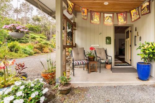 une terrasse couverte d'une maison avec deux chaises et des plantes dans l'établissement The Alala at Stained Glass Cottages, à Volcano