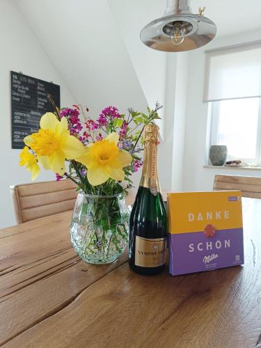 a bottle of wine and a vase of flowers on a table at Dorfliebe Reicherstein in Pöttmes