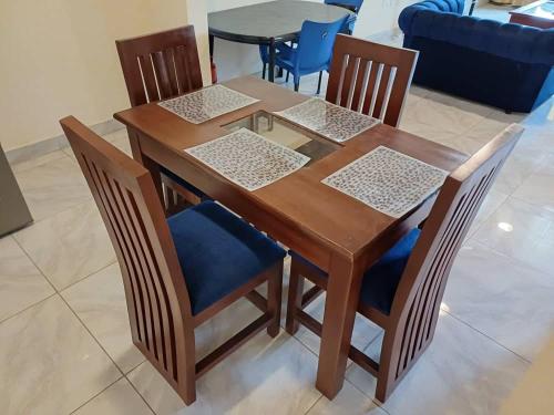 a wooden dining room table with four chairs and a blue couch at Lashibi Villas in Teshi