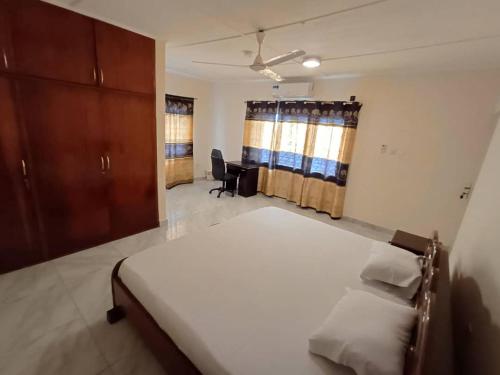 a bedroom with a bed and a desk in it at Lashibi Villas in Teshi