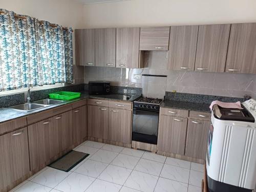 a kitchen with wooden cabinets and a sink and a stove at Lashibi Villas in Teshi
