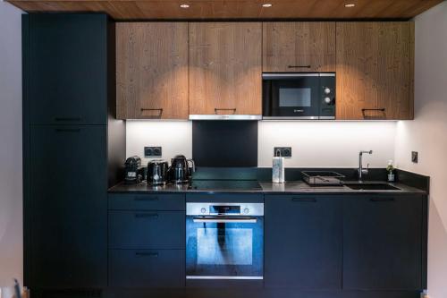 eine Küche mit schwarzen Schränken, einem Herd und einer Mikrowelle in der Unterkunft Exclusive accommodation terrace, parking and pool in Megève