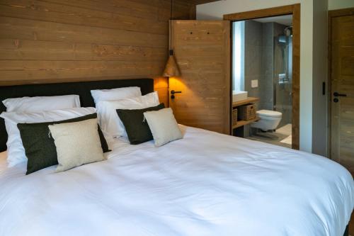 une chambre avec un grand lit blanc avec des oreillers dans l'établissement Exclusive accommodation terrace, parking and pool, à Megève