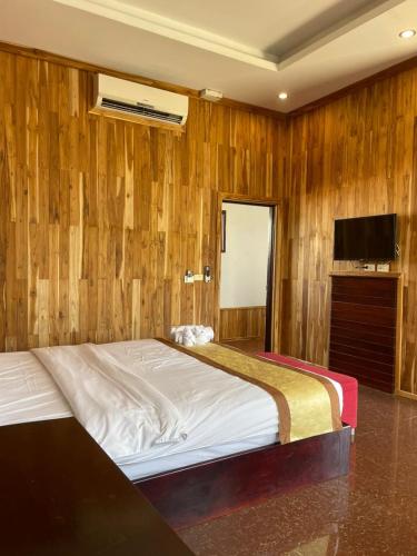 a bedroom with a bed with a wooden wall at Luang Prabang Inn 1 in Luang Prabang