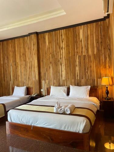 a bedroom with two beds and a wooden wall at Luang Prabang Inn 1 in Luang Prabang