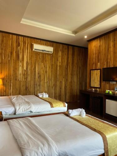 two beds in a hotel room with wooden walls at Luang Prabang Inn 1 in Luang Prabang