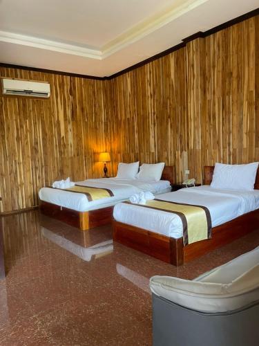 two beds in a room with wooden walls at Luang Prabang Inn 1 in Luang Prabang
