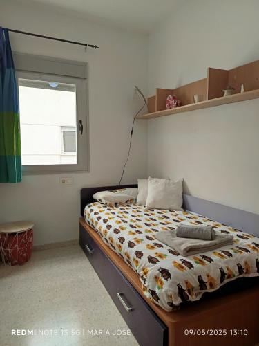 a bedroom with a bed with a comforter and a window at Disfruta Granada, Parking y Mascotas in Granada