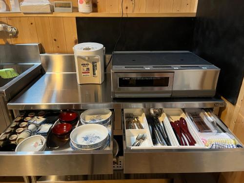 a kitchen with a counter with utensils and a stove at Matsumuraya Koma in Shiojiri
