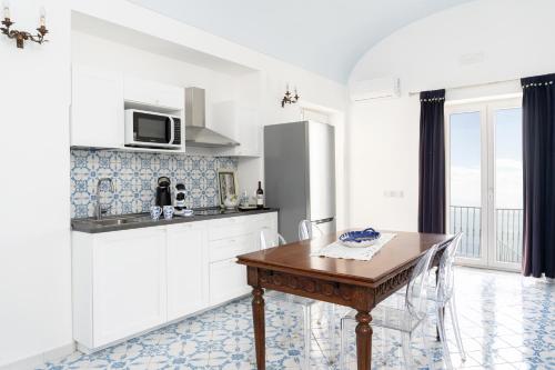 una cucina con mobili bianchi e un tavolo di legno di Villa Alba - Amalfi Coast ad Amalfi