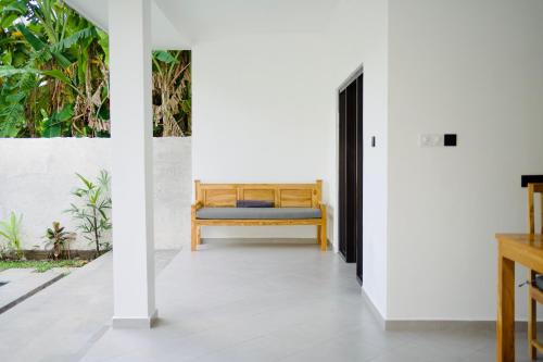 a hallway with a bench in a room with white walls at Lush Tropical Villa Central Amed in Amed