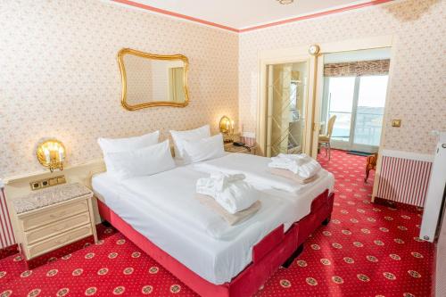 a bedroom with a large white bed with a mirror at Hotel Strandperle in Cuxhaven