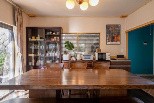 a dining room with a large wooden table and chairs at ゲストハウス三浦 サウナ Bbq 一棟貸し 最大13名 in Miura