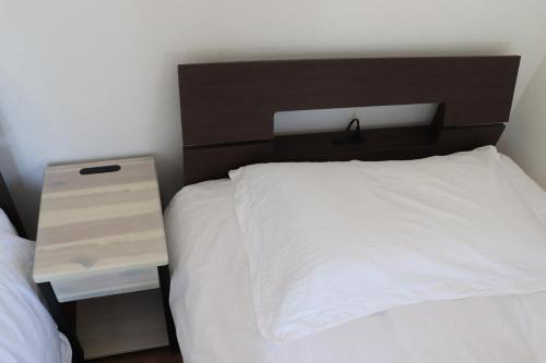 a bedroom with a white bed with a brown headboard at sakurayuki in Otaru