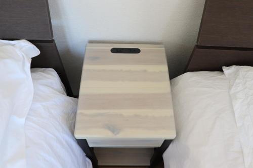 a nightstand between two beds in a hotel room at sakurayuki in Otaru