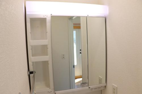 a bathroom mirror with a light on a wall at sakurayuki in Otaru