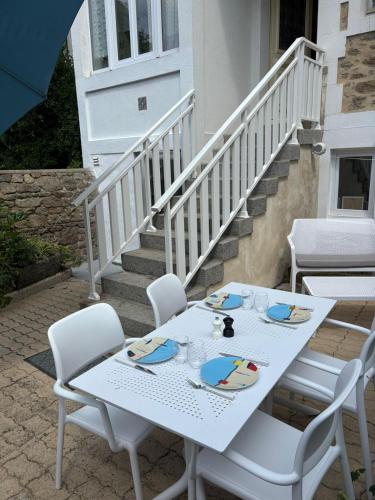 une table et des chaises blanches sur une terrasse avec des escaliers dans l'établissement Les Thermes- Apartment, à Saint-Malo