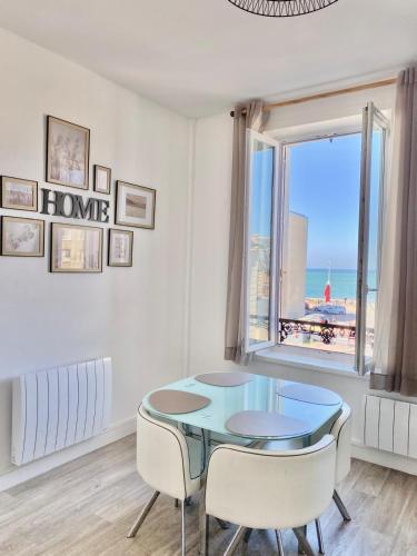 une salle à manger avec une table et des chaises et une fenêtre dans l'établissement Le Rayon Vert vue mer, à Fécamp