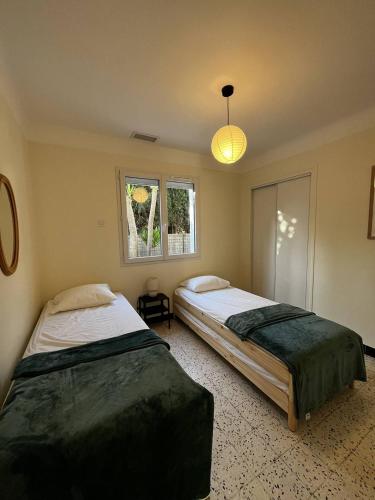 - une chambre avec deux lits et une lumière dans l'établissement Maison T4 plain pied climatisée avec une belle terrasse ombragée 6AVR44, à Canet