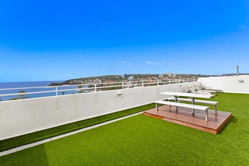 a balcony with a bench on the grass at The Manly beach pad in Sydney