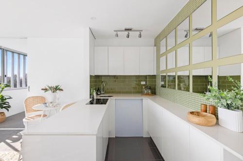 a kitchen with white cabinets and a large window at The Manly beach pad in Sydney