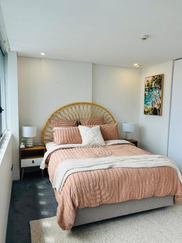 a bedroom with a large bed with pink blankets and pillows at The Manly beach pad in Sydney