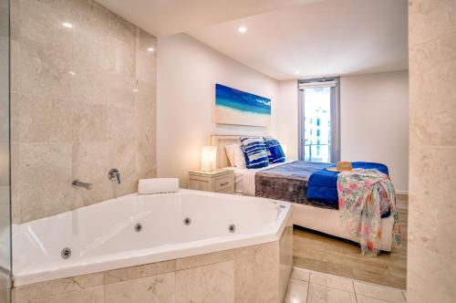 a large bathroom with a tub and a bed at Cilento Mooloolaba in Mooloolaba