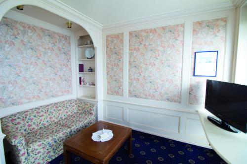 a room with a couch and a tv and a table at Hotel Strandperle in Cuxhaven