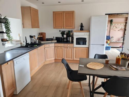 une cuisine avec des armoires en bois et une table avec des chaises dans l'établissement Maison de 2 gites privatifs et communicants 14 places, à Pouilly-les-Feurs