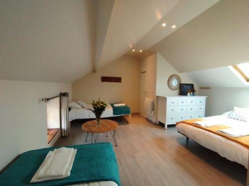 - une chambre mansardée avec 2 lits et une table dans l'établissement Leo's Cottage Second Souffle Valcanville, à Valcanville