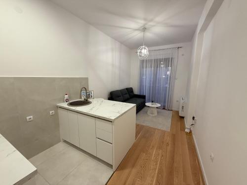 a white kitchen with a sink and a living room at apartman Sara in Trebinje