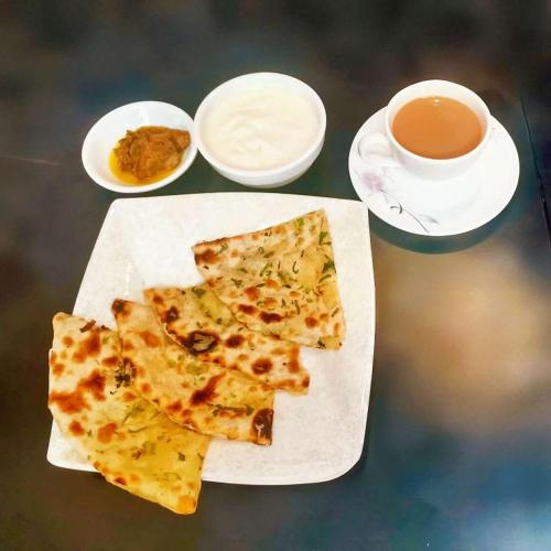 due fette di pizza su un piatto con una tazza di tè di 家德里酒店Dilli home hotel a Zhongshan