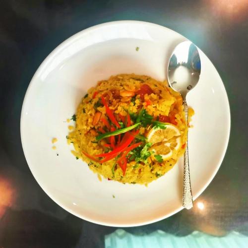 un piatto bianco con una ciotola di cibo con un cucchiaio di 家德里酒店Dilli home hotel a Zhongshan